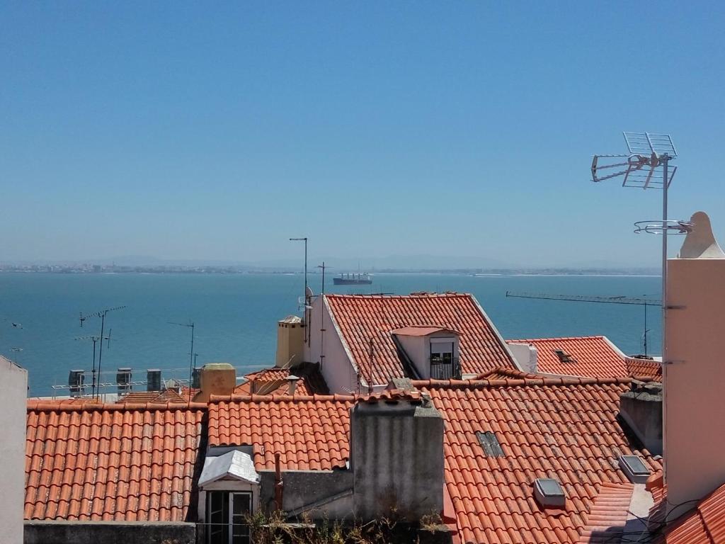 Blick auf die Dächer von Gebäuden und das Wasser in der Unterkunft Alfama Terrace in Lissabon