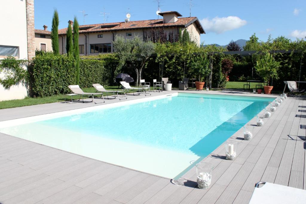 a swimming pool with chairs and a house in the background at B&B a Ca' Minore Franciacorta in Passirano