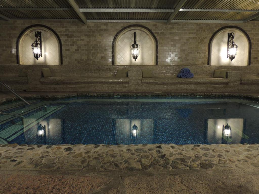 a swimming pool in a building with three lights at Tuscan Springs Hotel & Spa in Desert Hot Springs