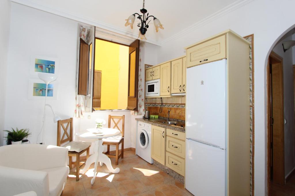 uma cozinha com uma mesa e um frigorífico branco em ApartamentosMalaga em Málaga