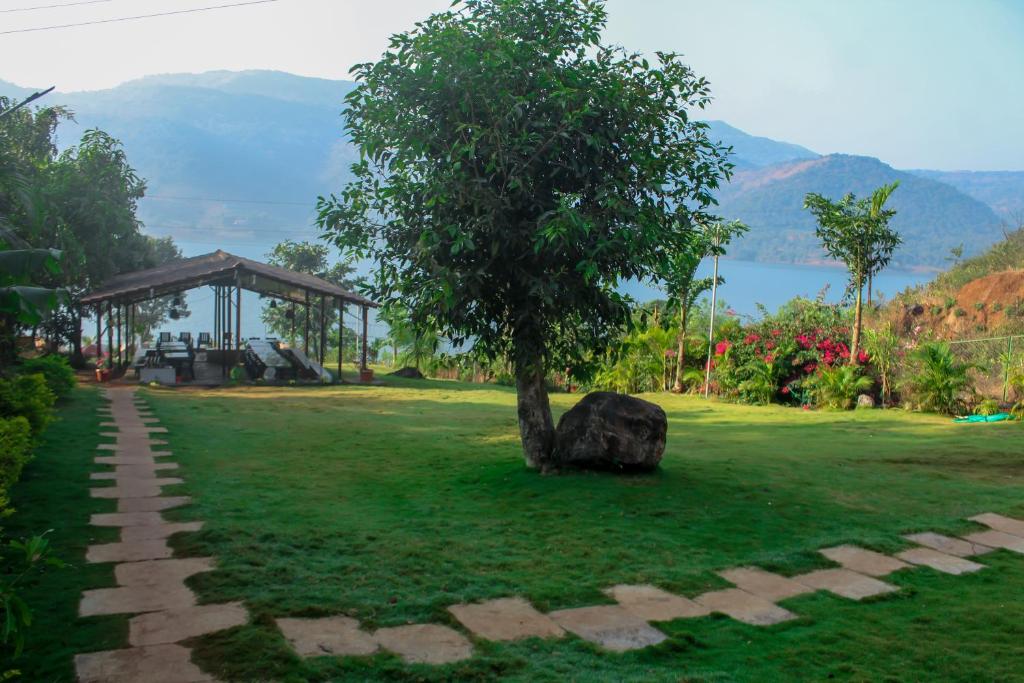 Ein Baum mitten auf einem Feld mit einem Felsen in der Unterkunft Lakeview Resort Lavasa in Lavasa