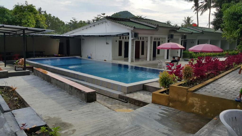 a swimming pool in front of a house at Jo Homestay in Selong Belanak