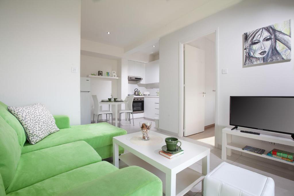 sala de estar con sofá verde y TV en Myrtiana Apartments en Nicosia