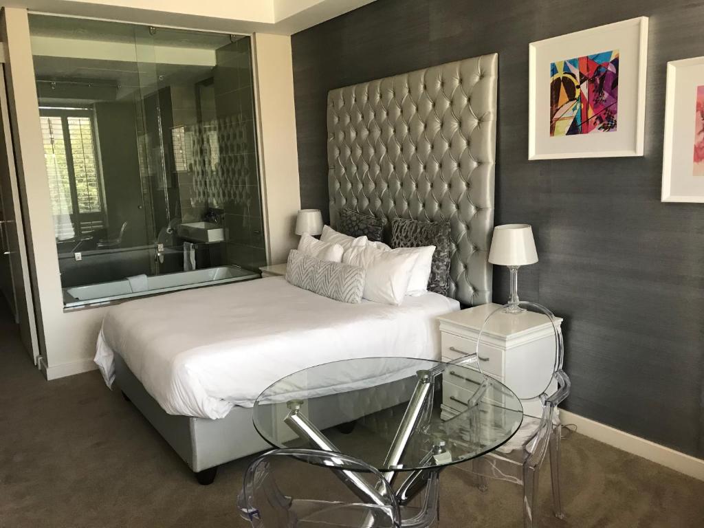 1 dormitorio con 1 cama grande y mesa de cristal en Sandton Skye en Johannesburgo