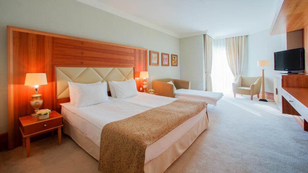 a hotel room with a large bed and a television at Rixos-Prykarpattya Resort in Truskavets