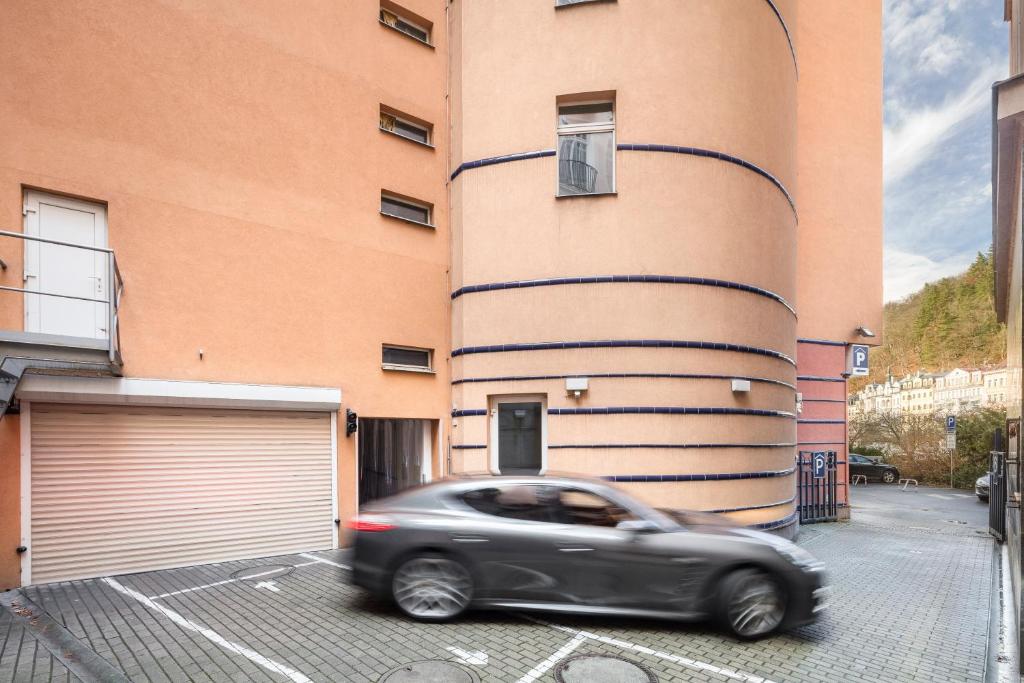 a car driving past a building with a garage at Interhotel Central in Karlovy Vary