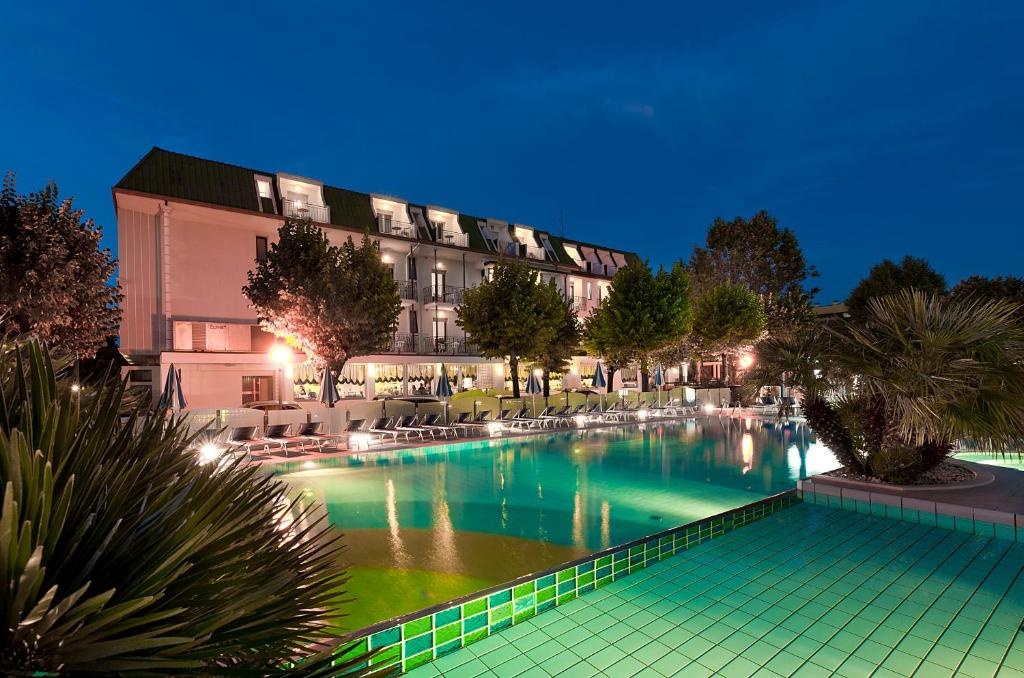 a swimming pool in front of a building at night at Hotel Paris Resort in Bellaria-Igea Marina