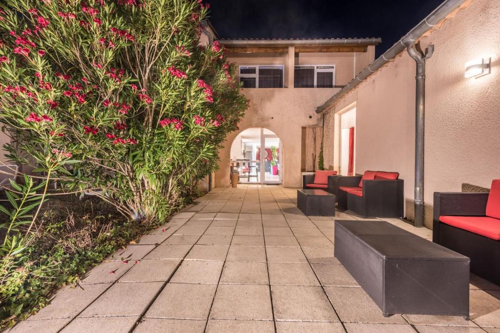a patio with red chairs and pink flowers at Le Clos des Bruyères in Vallon-Pont-dʼArc