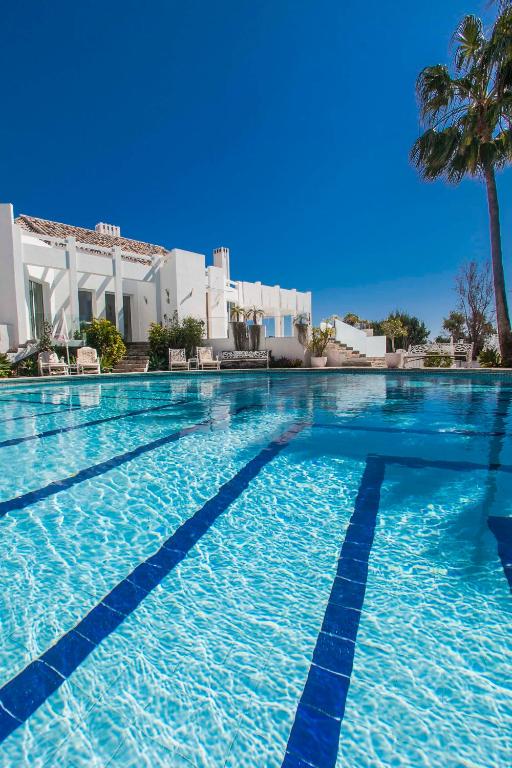 a swimming pool with blue water and a palm tree at Villa Capricho in Marbella
