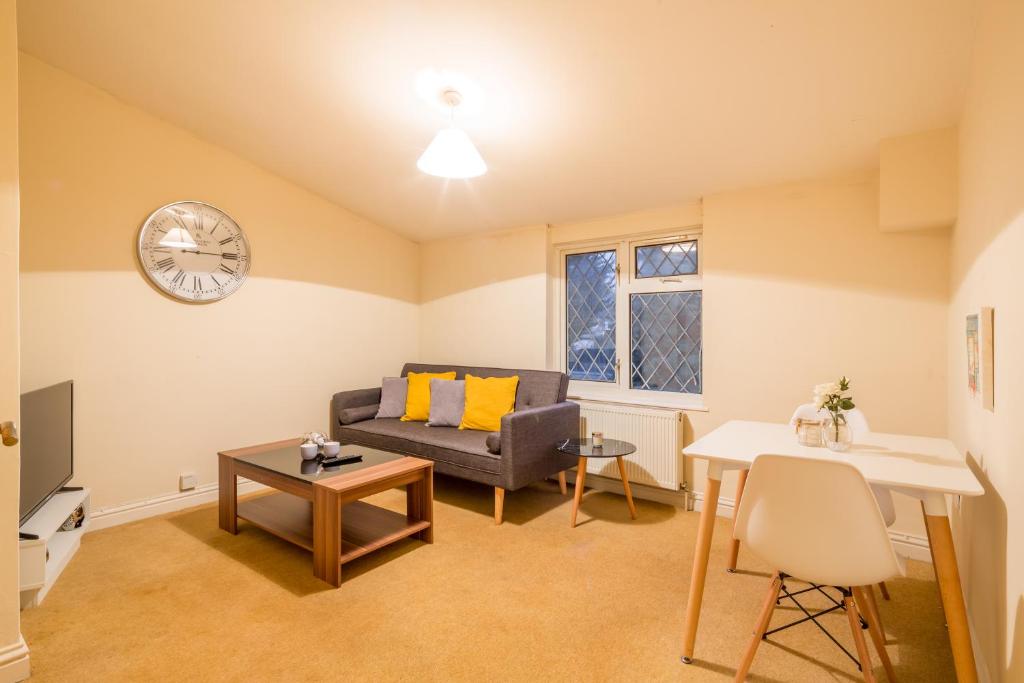 a living room with a couch and a clock on the wall at Skyline Serviced Apartments - Colestrete in Stevenage