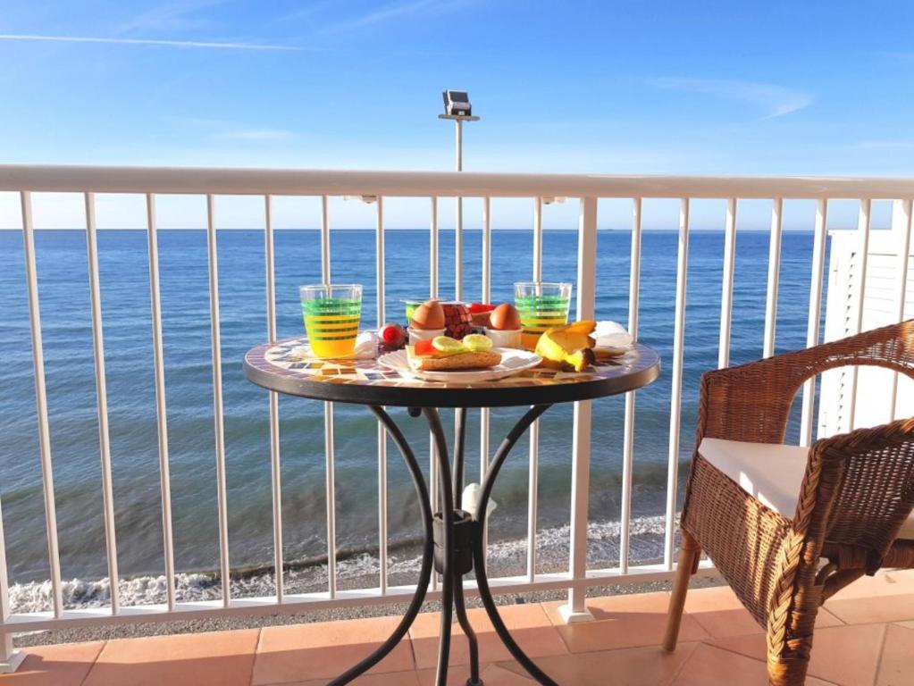 ネルハにあるApartment over torrecilla beach promenadeの海を見渡すバルコニーにテーブルと食べ物を用意しています。
