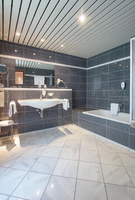 ein Badezimmer mit einer Badewanne, einem Waschbecken und einem Badetubermott in der Unterkunft Hotel Stadt Breisach in Breisach am Rhein