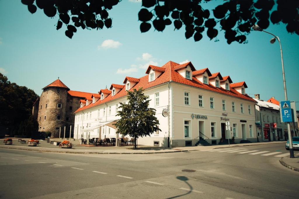 ein weißes Gebäude mit rotem Dach und einem Schloss in der Unterkunft Heritage Hotel Frankopan in Ogulin