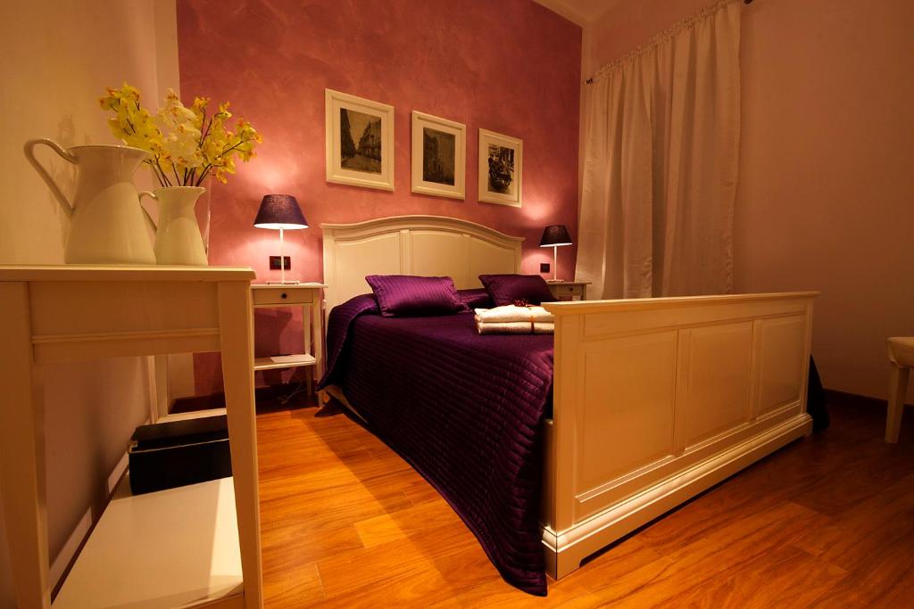 1 dormitorio con 1 cama con almohadas moradas en B&B Cortile Di Venere, en Trapani