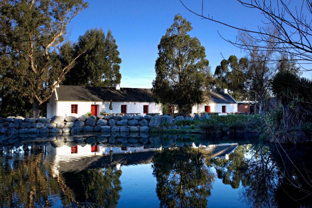 a house with a stone wall next to a pond at Donegal House in Kaikoura