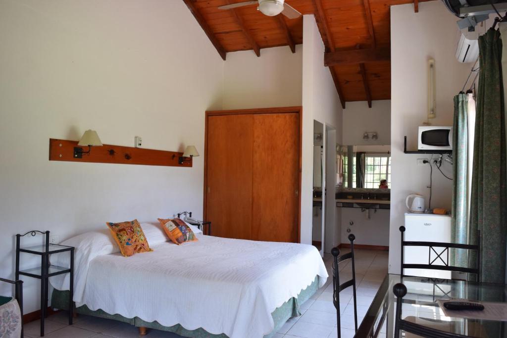 a bedroom with a bed with white sheets and wooden ceilings at Posada Los Alamos in Merlo
