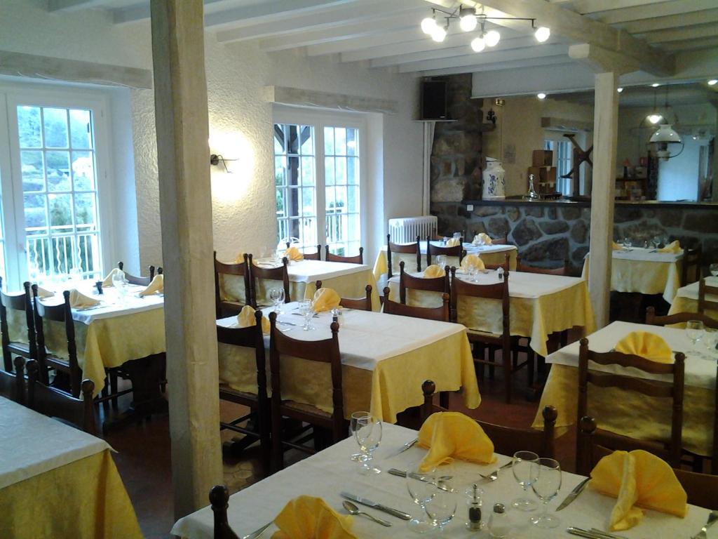a dining room with tables and chairs with yellow table cloth at La Cremaillere in Miremont