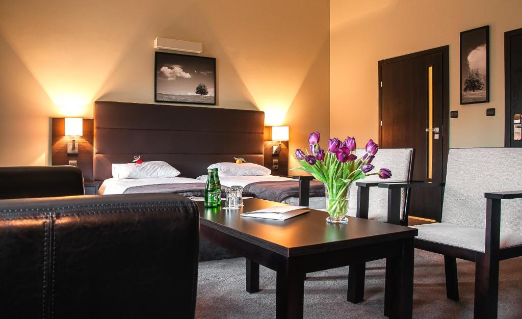 una camera d'albergo con letto e tavolo con fiori di Hotel Ilan a Lublino