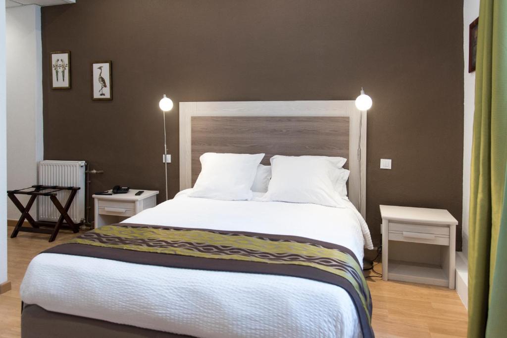 - une chambre dotée d'un grand lit avec des draps et des oreillers blancs dans l'établissement Grand Hotel Pelisson, à Nontron