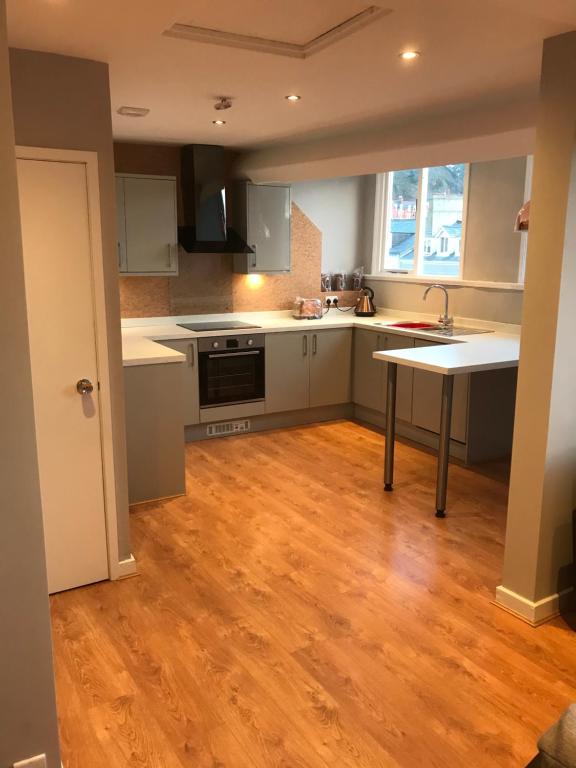 a kitchen with white cabinets and a wooden floor at Apartment 5, Cornerhouse Apartments in Llandudno
