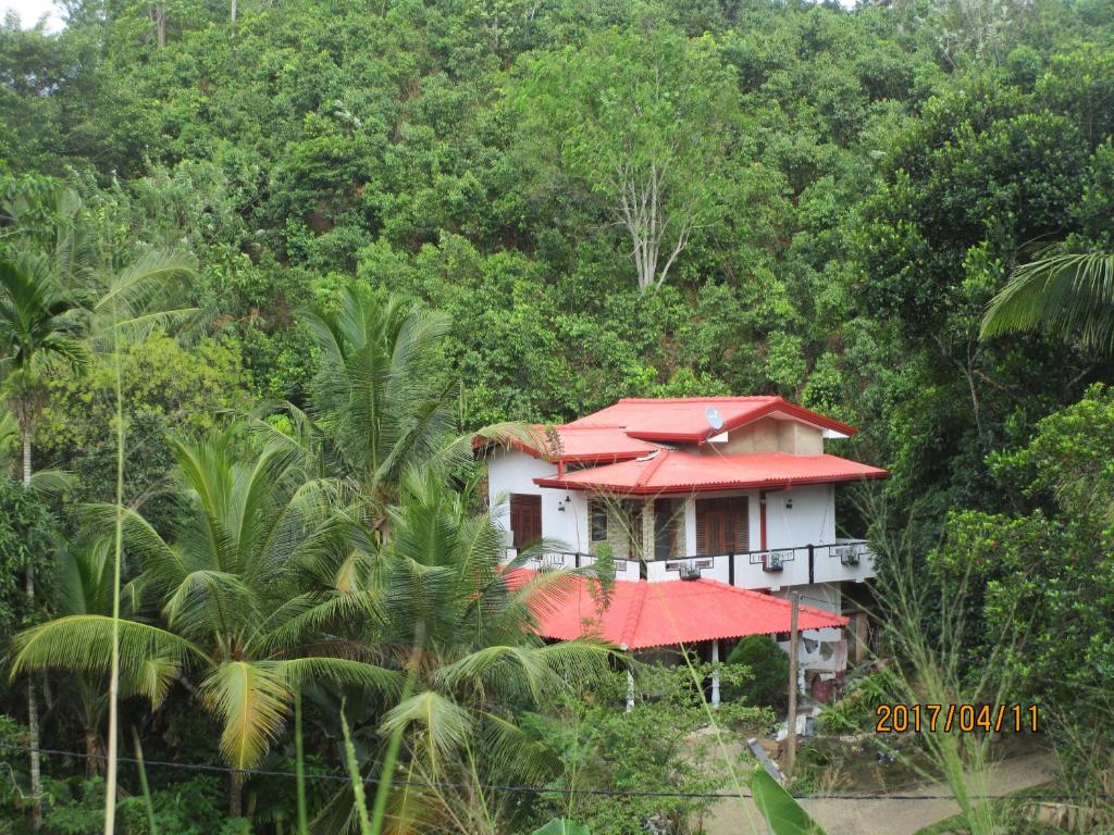 una casa con tetto rosso nella foresta di Maneesha Guest House a Weligama