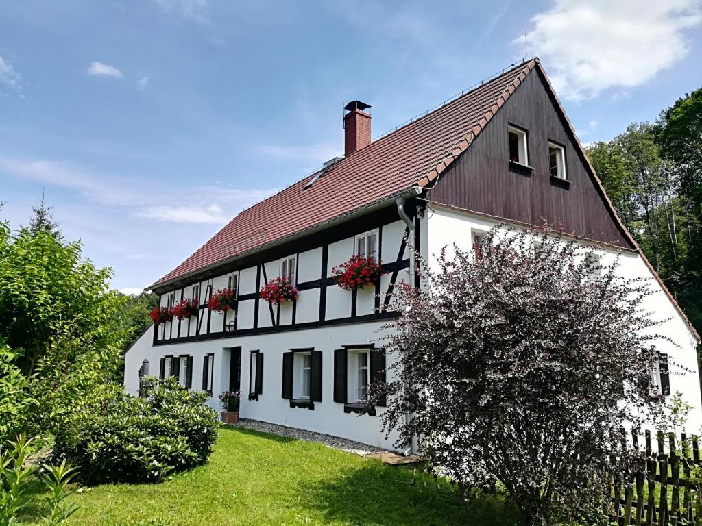 a white house with red flowers on the windows at Lusatia Farm in Leśna