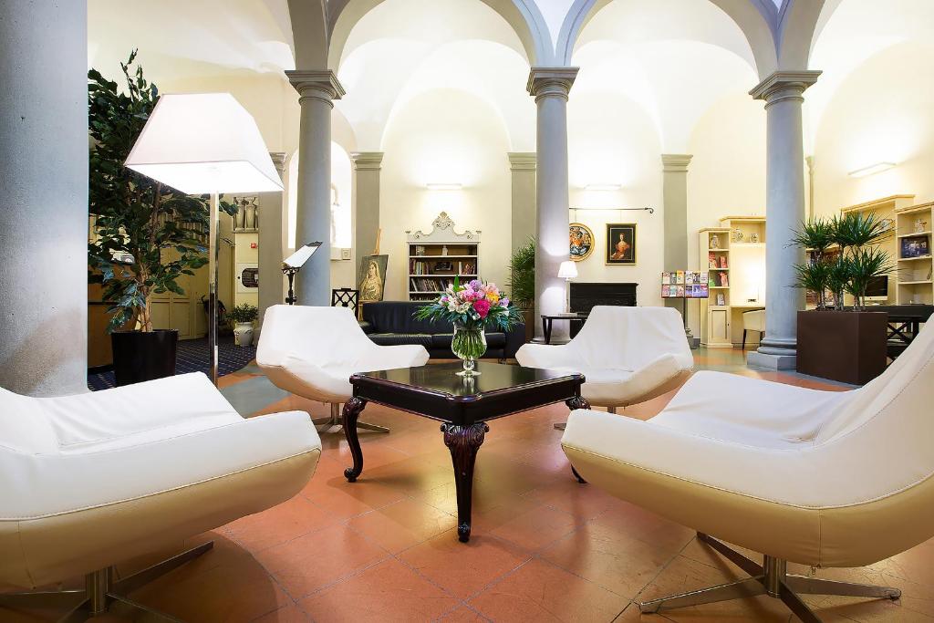 uma sala de estar com cadeiras brancas e uma mesa em Relais Hotel Centrale "Dimora Storica" em Florença