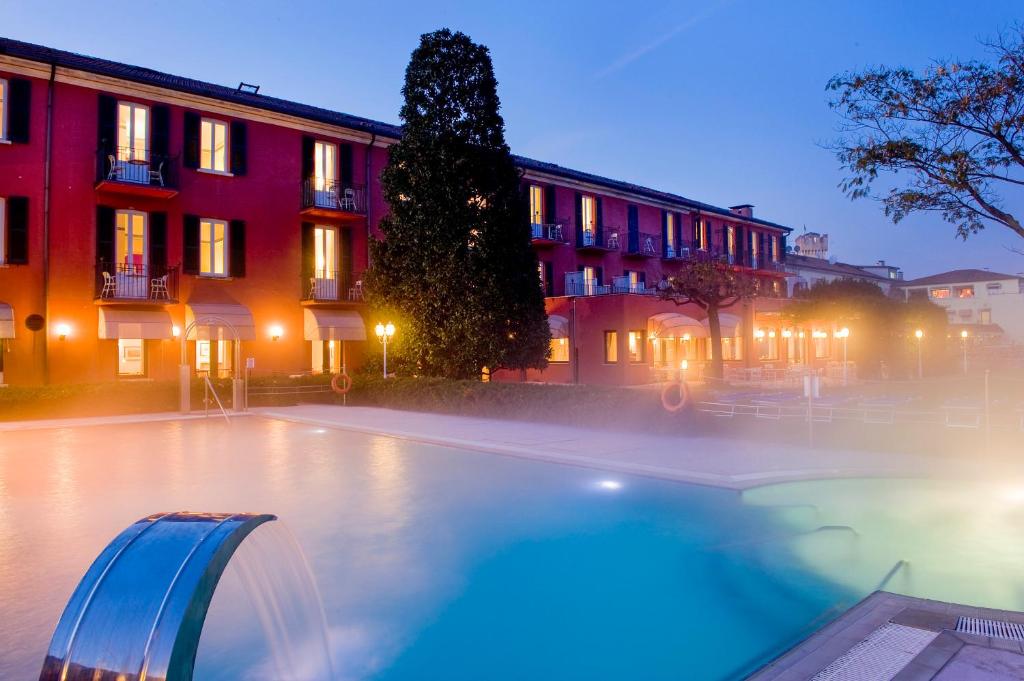 a swimming pool in front of a building at night at Hotel Fonte Boiola in Sirmione