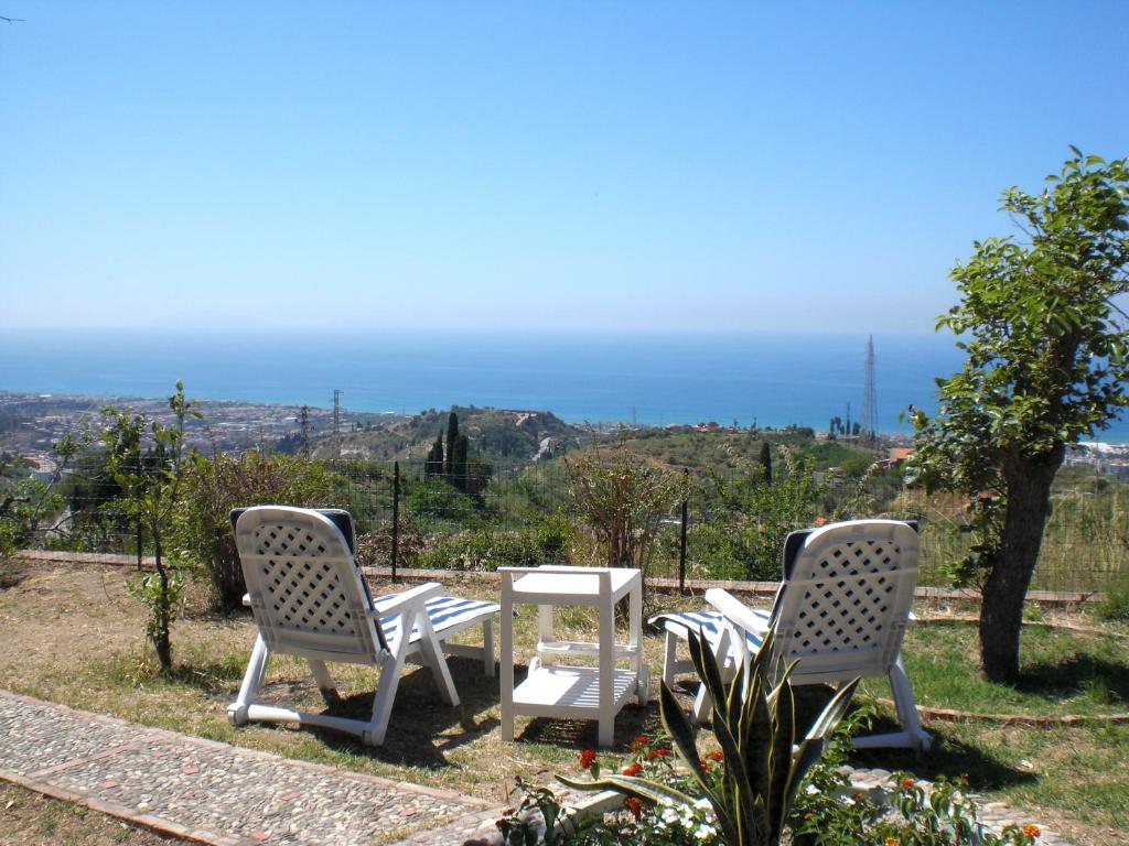 2 Stühle und ein Tisch mit Meerblick in der Unterkunft Villa Serro in Villafranca Tirrena