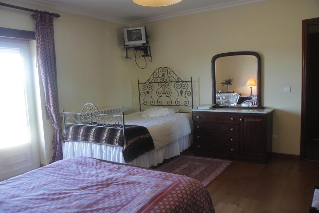 um quarto com uma cama, uma cmoda e um espelho em Quartos em vivenda serra da Estrela em Celorico da Beira
