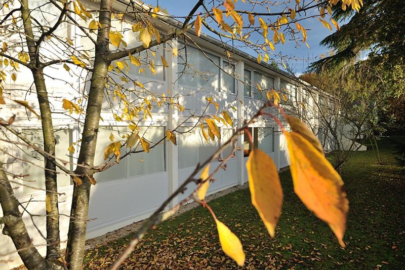 a tree with autumn leaves in front of a building at Contact Hôtel du Parc in Orvault