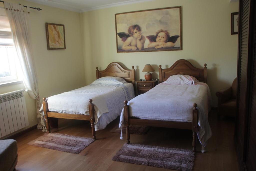 um quarto com duas camas e um quadro na parede em Quartos em vivenda serra da Estrela em Celorico da Beira
