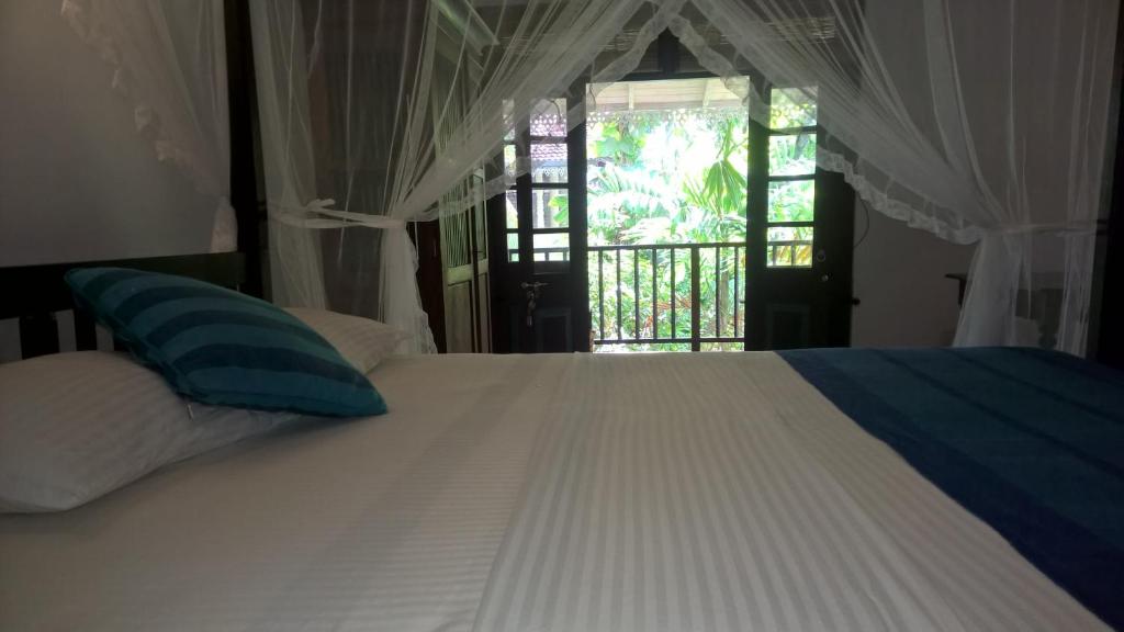 a bedroom with a white bed with a window at Silva Rest in Unawatuna