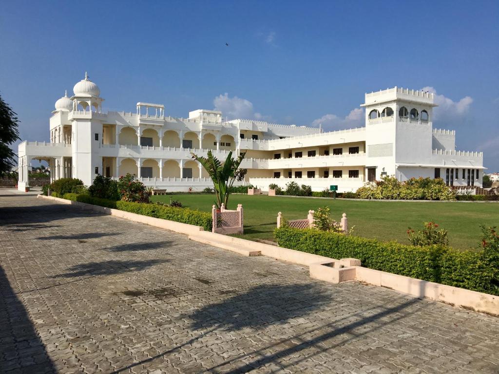 ein großes weißes Gebäude mit einem Rasen davor in der Unterkunft Dowlat Villas Palace-The Heritage in Himatnagar