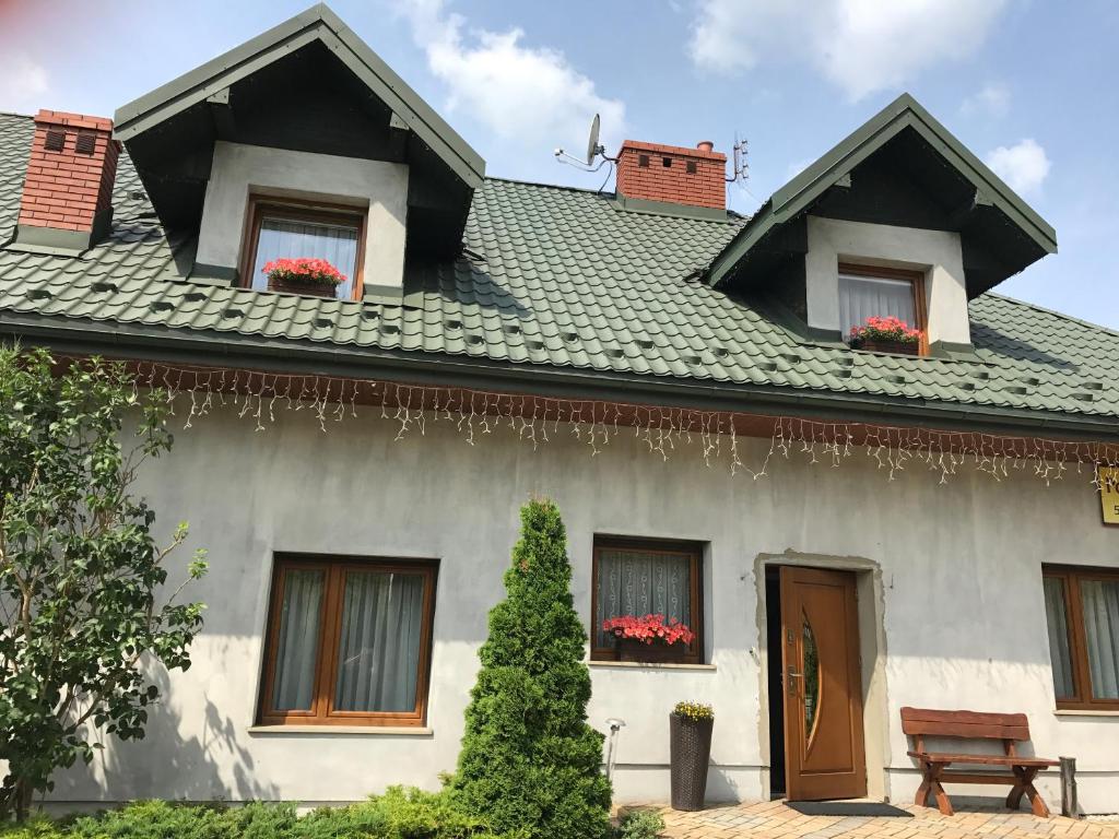 a house with flowers in windows and a roof at Pokoje do wynajęcia Magdalena Nowak in Krynica Zdrój