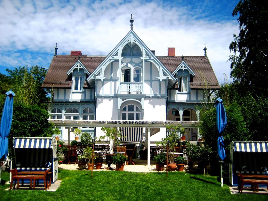 een groot wit huis met twee stoelen in de tuin bij Hotel Barleben am See in Konstanz