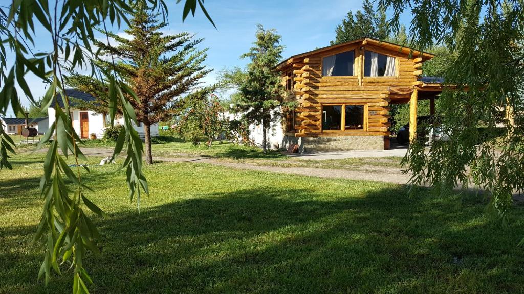 a log cabin in a field of grass with a tree at Cabañas Años Verdes in Sarmiento