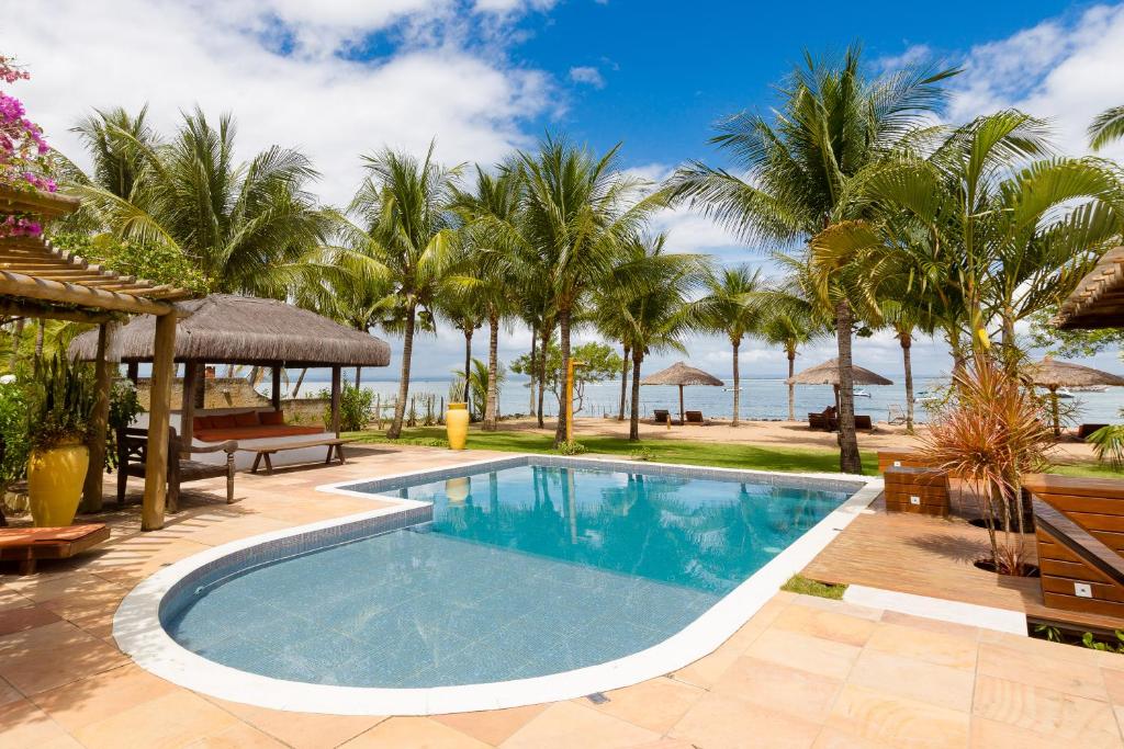 una piscina con palmeras y el océano en el fondo en Pousada Denada, en Barra Grande