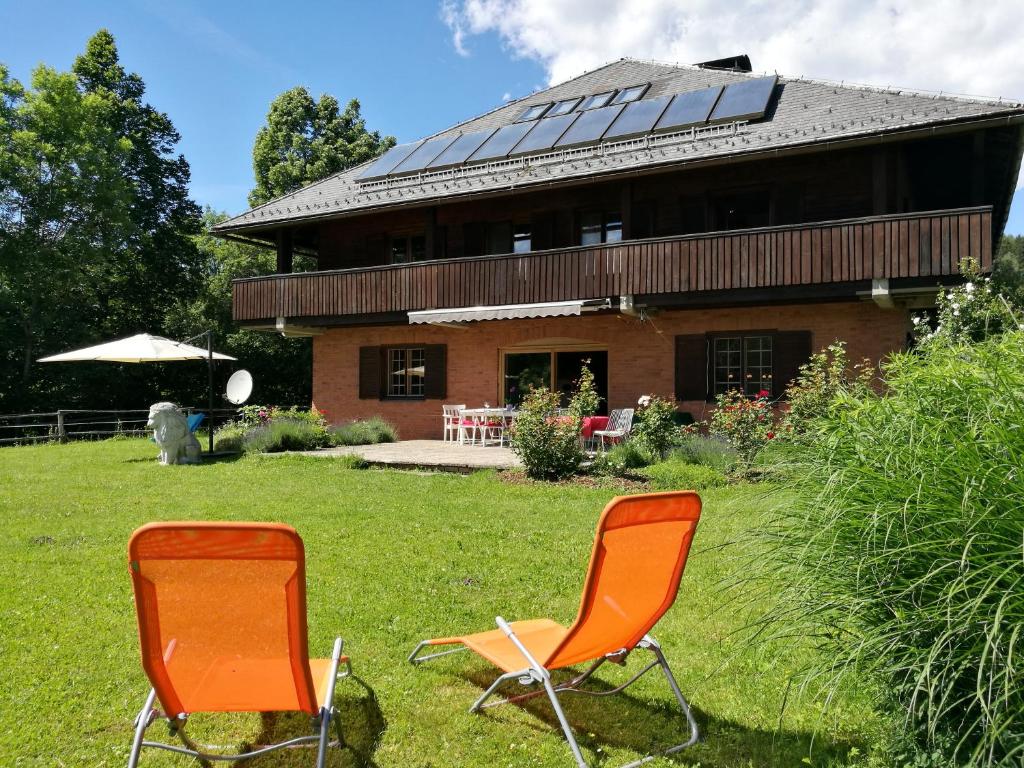 zwei orangefarbene Stühle im Gras vor einem Haus in der Unterkunft Villa Leone in Maria Rain