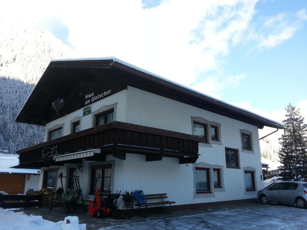 a white building with a black roof in the snow at Haus am Gletscher in Neustift im Stubaital