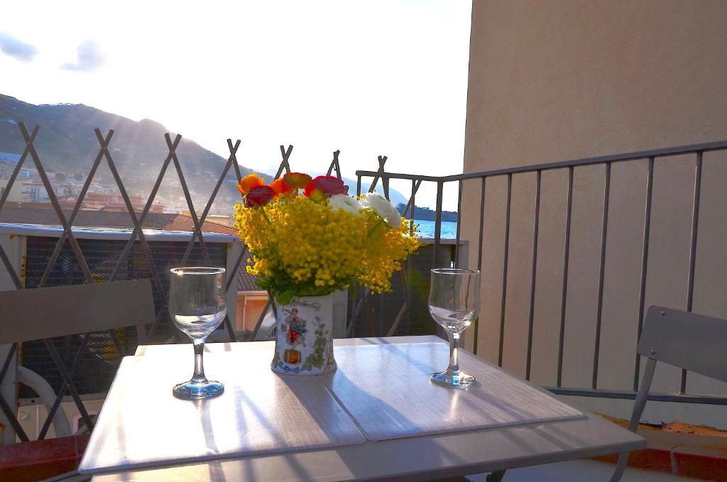 a table with two wine glasses and a vase of flowers at Guest House Spinuzza in Cefalù