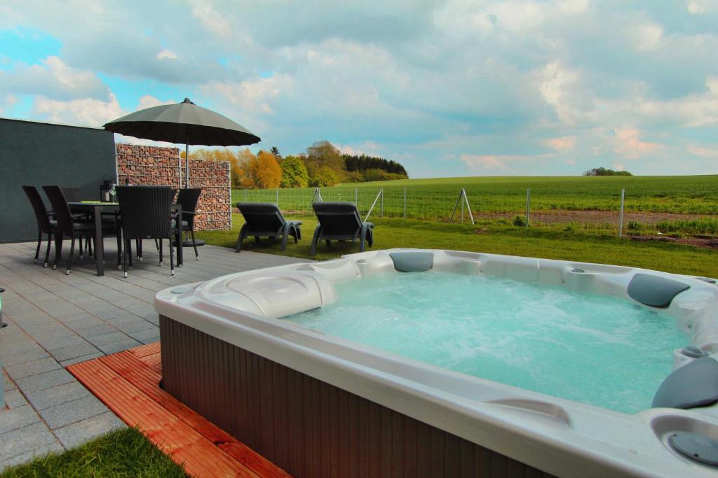 - un grand bain à remous sur une terrasse avec une table et un parasol dans l'établissement Ferien_HAUS LIMERICK, à Göhren-Lebbin