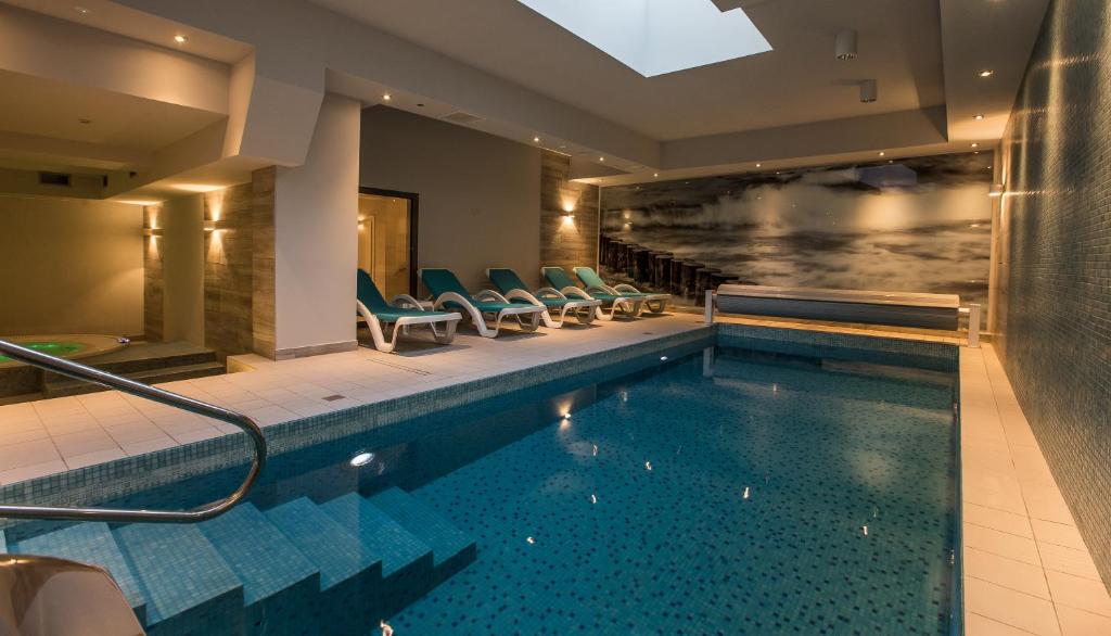 una piscina en un hotel con sillas alrededor en Villa Bravo & SPA en Międzyzdroje