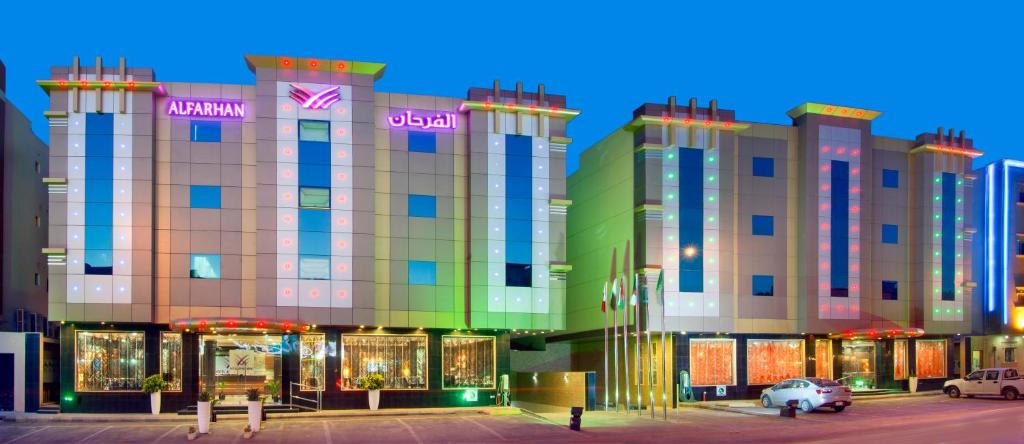 Al Farhan Suites Ishbillia في الرياض: مبنى كبير أمامه محلات تجارية