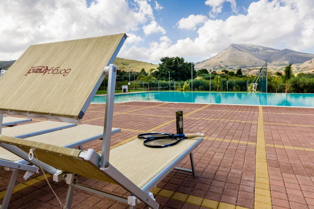 a bench with a laptop sitting on it next to a pool at Borgo Aranci - Villetta Peonia B3 - Castellammare del Golfo in Castellammare del Golfo
