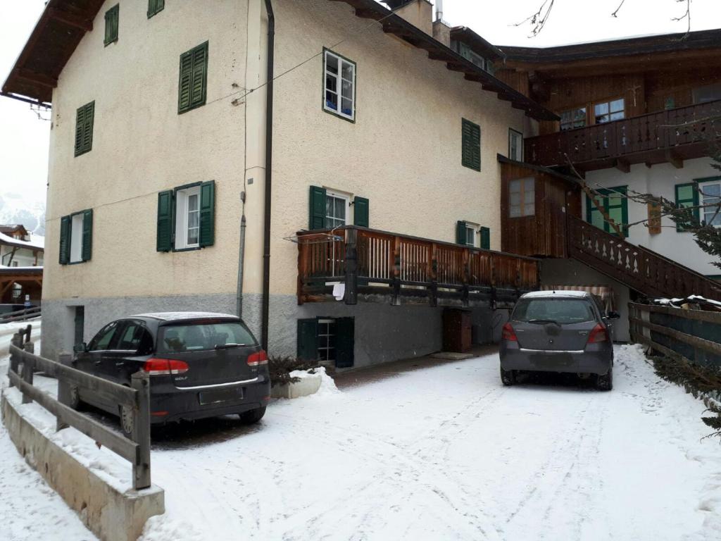 twee auto's geparkeerd buiten een gebouw in de sneeuw bij Ciasa de Anz in Pozza di Fassa