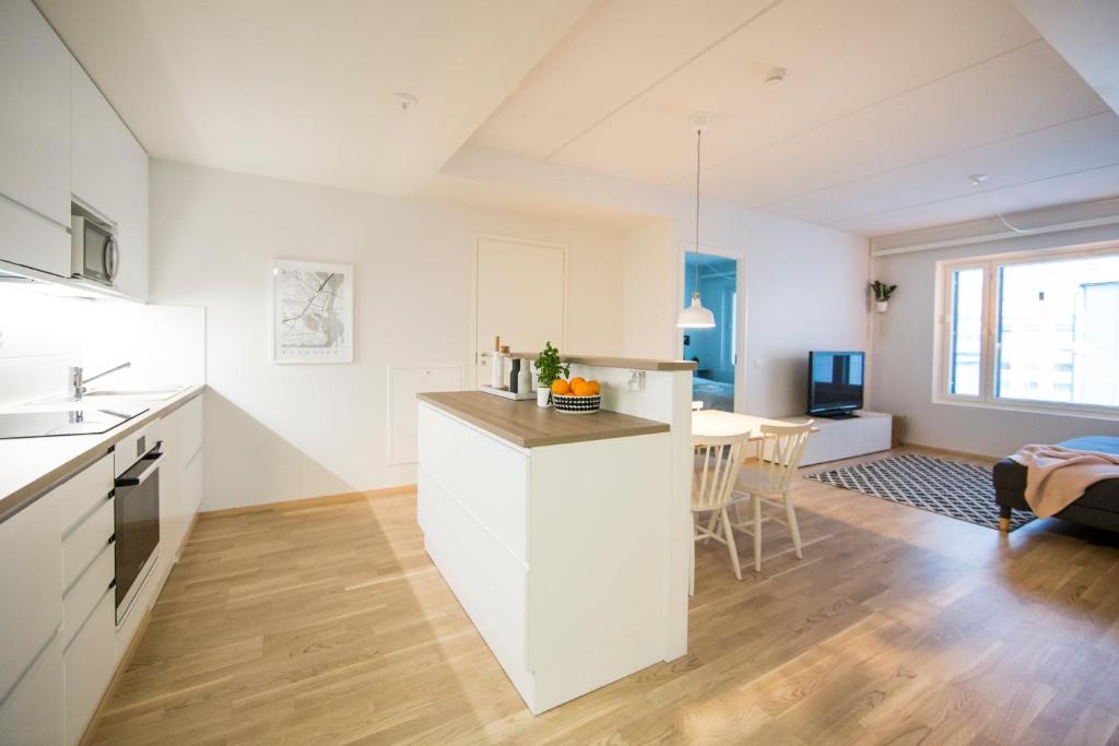 uma cozinha e sala de estar com armários brancos e uma mesa em Aurora City Center Suite em Rovaniemi