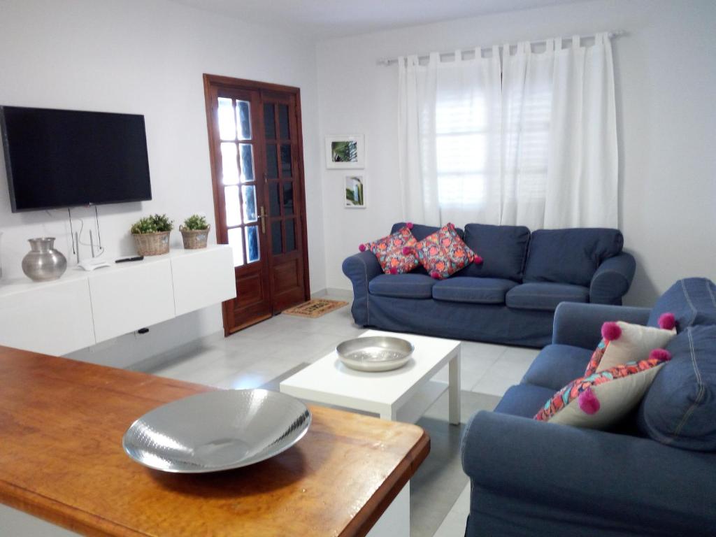 uma sala de estar com dois sofás azuis e uma mesa em Apartamento playa coqueto junto al mar em Playa Honda