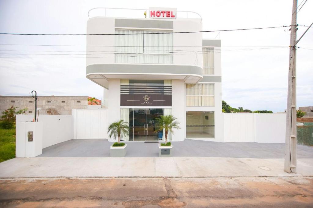 un edificio blanco con dos palmeras delante en Hotel Portal Guanambi en Guanambi