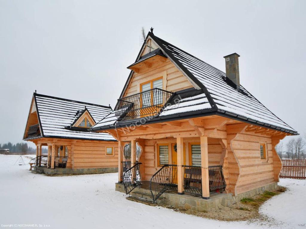 Cabaña de madera con nieve en el techo en Chocholowskie Domki, en Chochołów